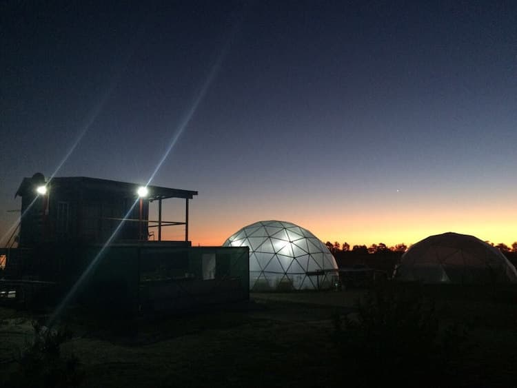 Geodesic domes alight with the sun setting in the background.