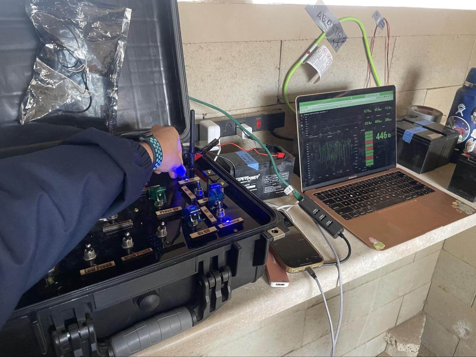 A photo of the author's hand holding a switch next to a laptop displaying a Grafana dashboard